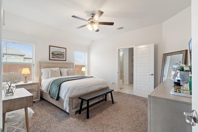 carpeted bedroom with multiple windows, ceiling fan, and ensuite bath