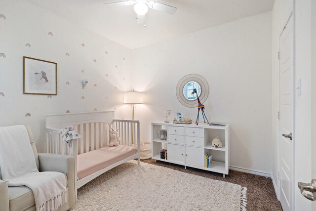 carpeted bedroom featuring a crib and ceiling fan