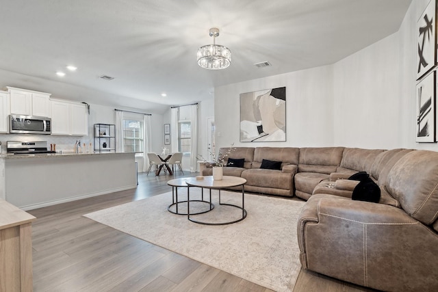 living room featuring a chandelier and light wood-type flooring