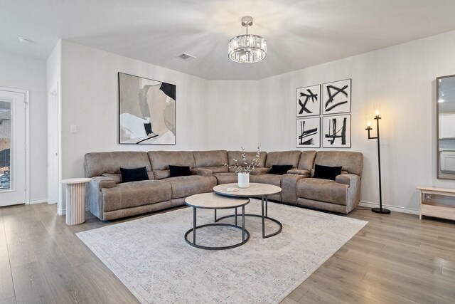 living room with light wood-type flooring and a notable chandelier