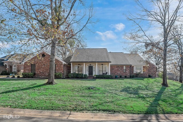 ranch-style home featuring covered porch and a front yard