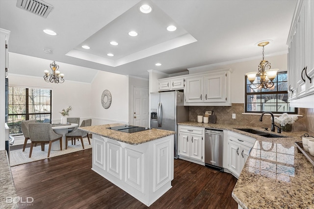 kitchen with white cabinetry, a kitchen island, sink, and a notable chandelier