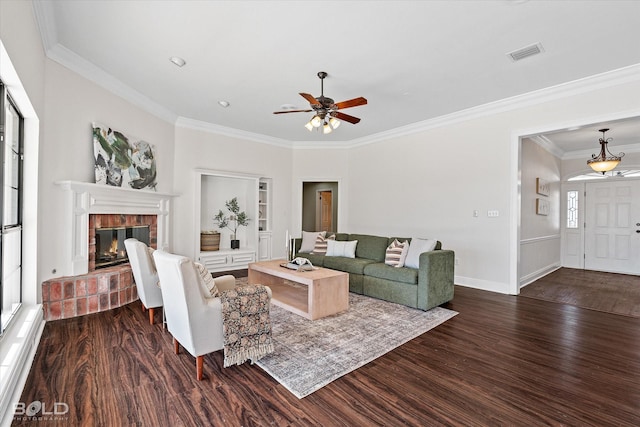 living room with built in shelves, ornamental molding, dark hardwood / wood-style flooring, and a brick fireplace