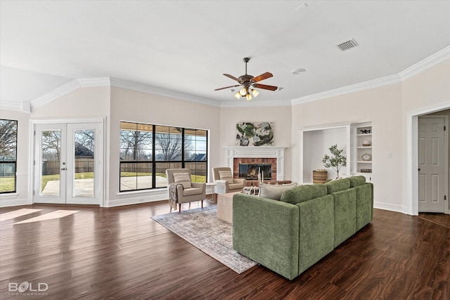 living room with crown molding, a brick fireplace, dark hardwood / wood-style flooring, and french doors