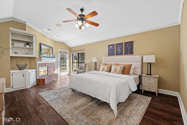 bedroom featuring crown molding, vaulted ceiling, a brick fireplace, dark hardwood / wood-style flooring, and access to exterior