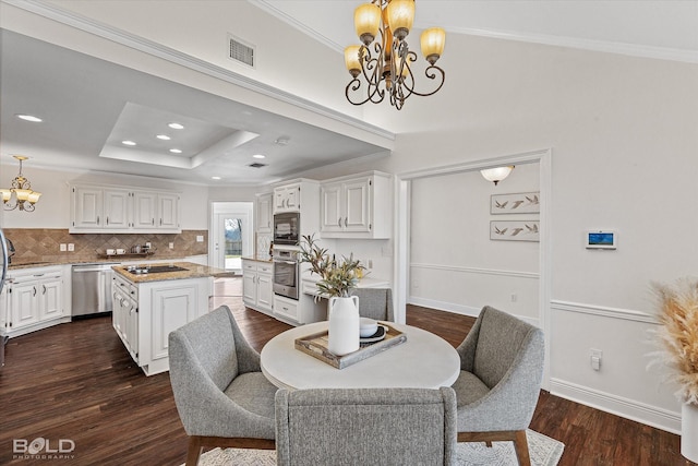 dining room with crown molding, dark hardwood / wood-style floors, a raised ceiling, and a notable chandelier