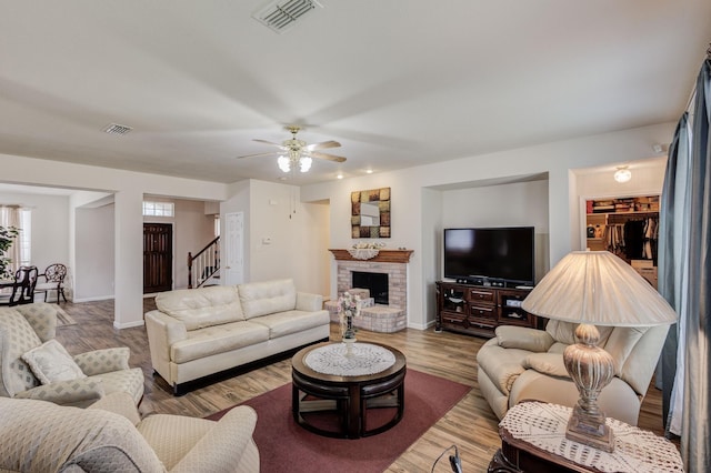 living room with ceiling fan, a fireplace, and hardwood / wood-style flooring