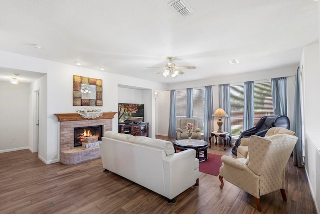 living room featuring dark hardwood / wood-style floors, a brick fireplace, and ceiling fan