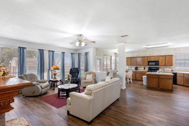 living room with a textured ceiling, ceiling fan, and dark wood-type flooring