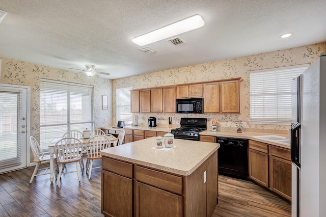 kitchen featuring a textured ceiling, ceiling fan, black appliances, a center island, and dark hardwood / wood-style floors