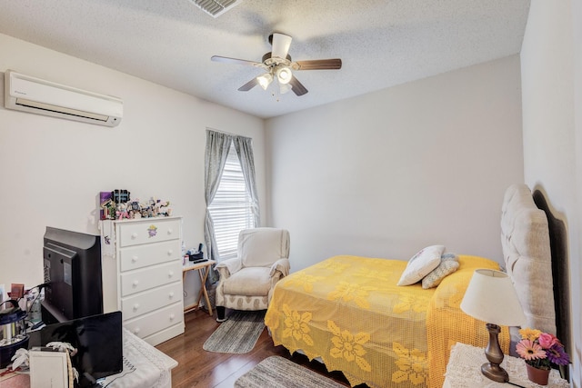 bedroom featuring ceiling fan, a textured ceiling, a wall unit AC, and dark wood-type flooring