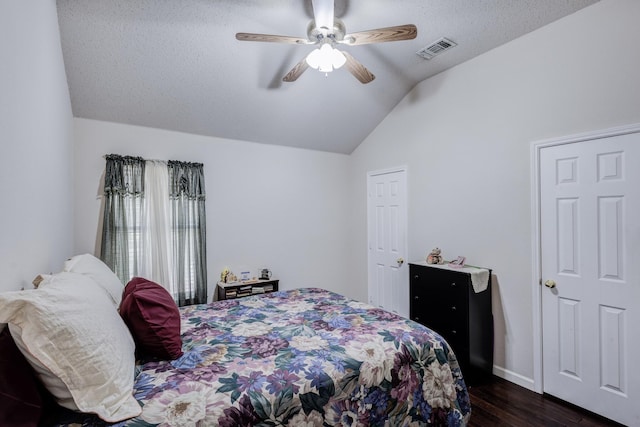 bedroom featuring ceiling fan, dark hardwood / wood-style floors, a textured ceiling, and vaulted ceiling