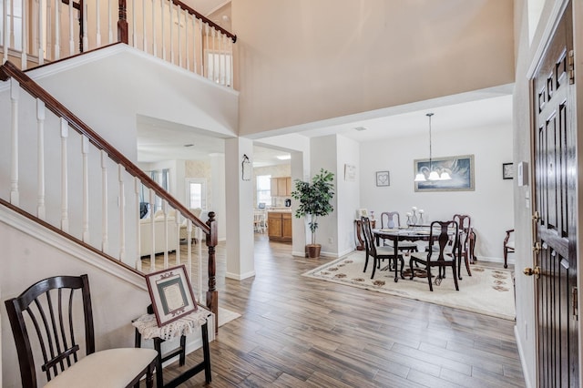 foyer with a chandelier, wood-type flooring, and a towering ceiling