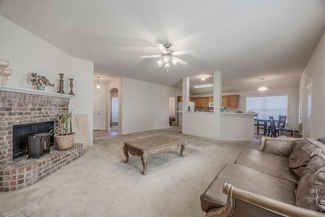 carpeted living room featuring a textured ceiling, a wood stove, and ceiling fan