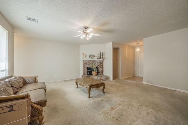 living room with ceiling fan, a wood stove, a textured ceiling, and light carpet