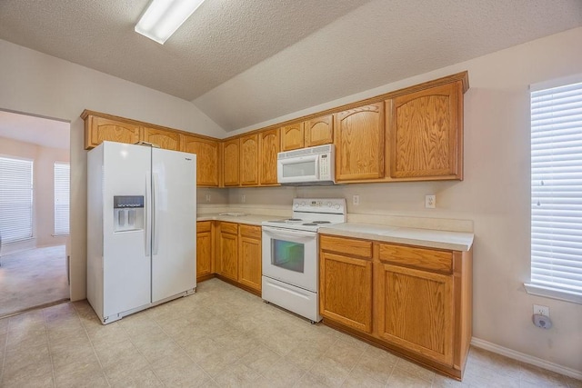 kitchen with a textured ceiling, white appliances, vaulted ceiling, and a healthy amount of sunlight