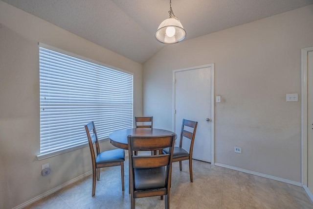 dining room with a textured ceiling, a wealth of natural light, and lofted ceiling