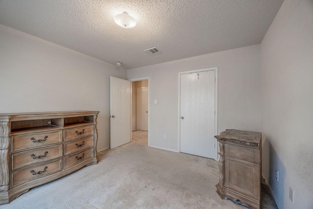 bedroom featuring a textured ceiling, light carpet, and a closet