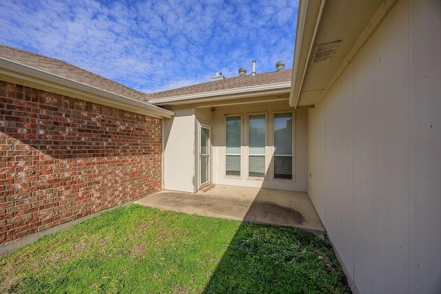 view of exterior entry with a yard and a patio