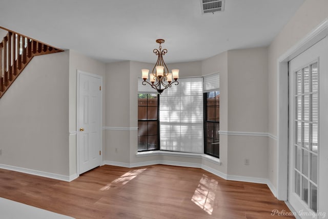 unfurnished dining area with a chandelier and light hardwood / wood-style floors