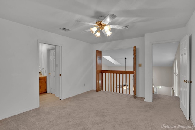 carpeted spare room featuring ceiling fan and a skylight