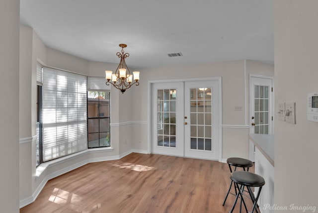 dining room featuring an inviting chandelier, light hardwood / wood-style flooring, and french doors