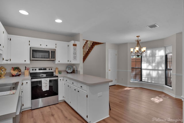 kitchen featuring pendant lighting, white cabinetry, stainless steel appliances, and kitchen peninsula