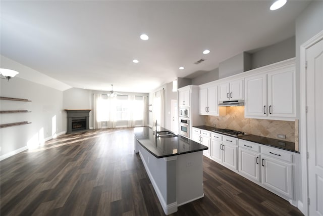 kitchen with visible vents, a sink, stainless steel appliances, under cabinet range hood, and dark countertops