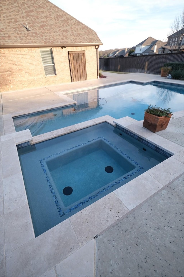 view of swimming pool with a pool with connected hot tub and fence