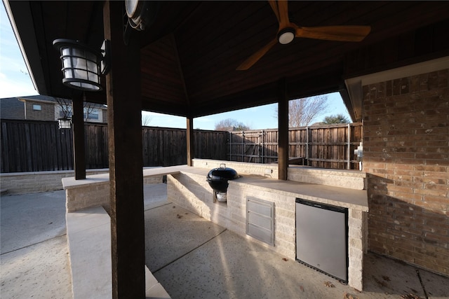 view of patio / terrace with a gazebo, an outdoor kitchen, a fenced backyard, and ceiling fan