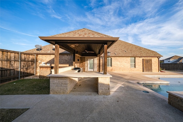 view of patio featuring a ceiling fan, a fenced in pool, exterior kitchen, a fenced backyard, and outdoor dry bar