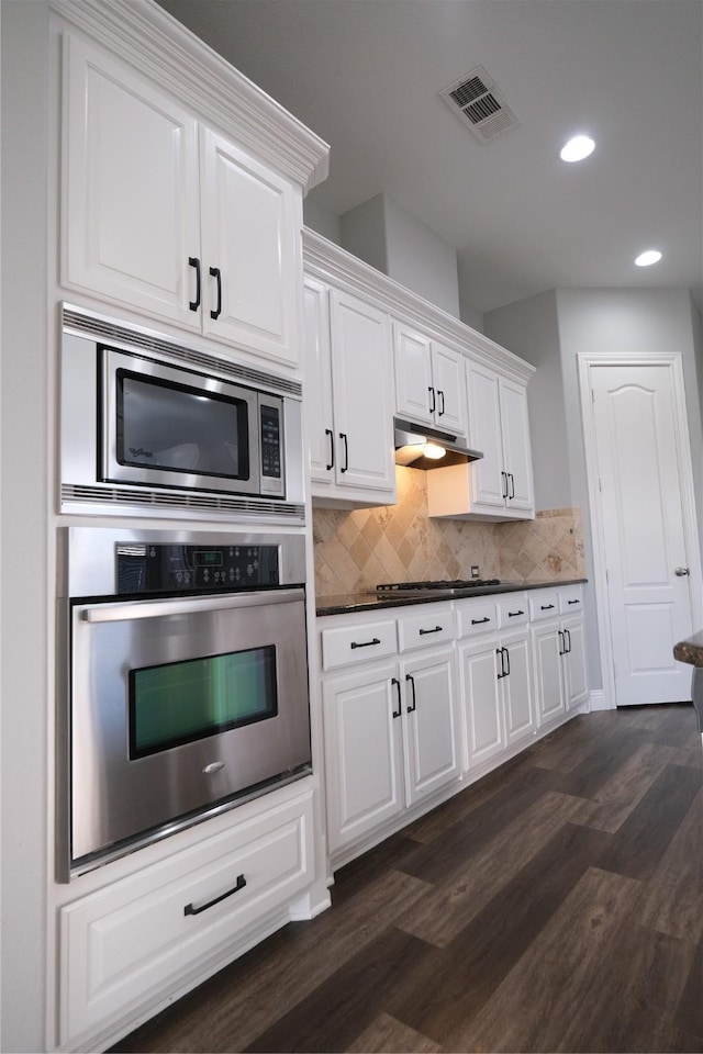 kitchen with visible vents, under cabinet range hood, tasteful backsplash, appliances with stainless steel finishes, and white cabinets