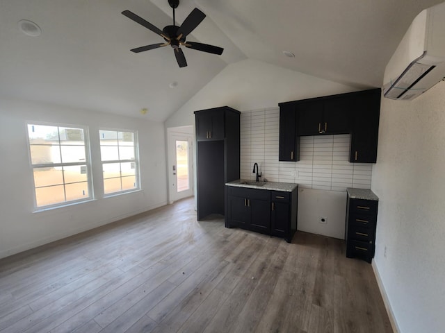 kitchen with lofted ceiling, an AC wall unit, sink, hardwood / wood-style flooring, and ceiling fan