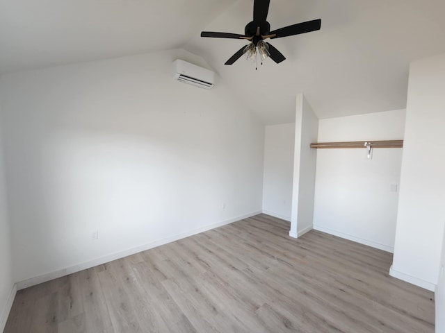 unfurnished bedroom with light wood-type flooring, vaulted ceiling, ceiling fan, an AC wall unit, and a closet