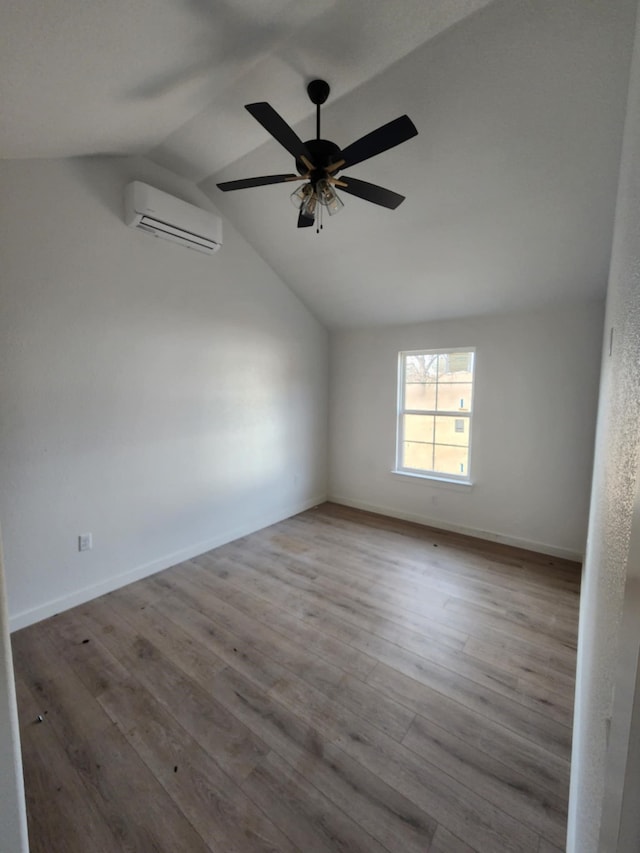 spare room featuring a wall mounted air conditioner, ceiling fan, light hardwood / wood-style floors, and vaulted ceiling