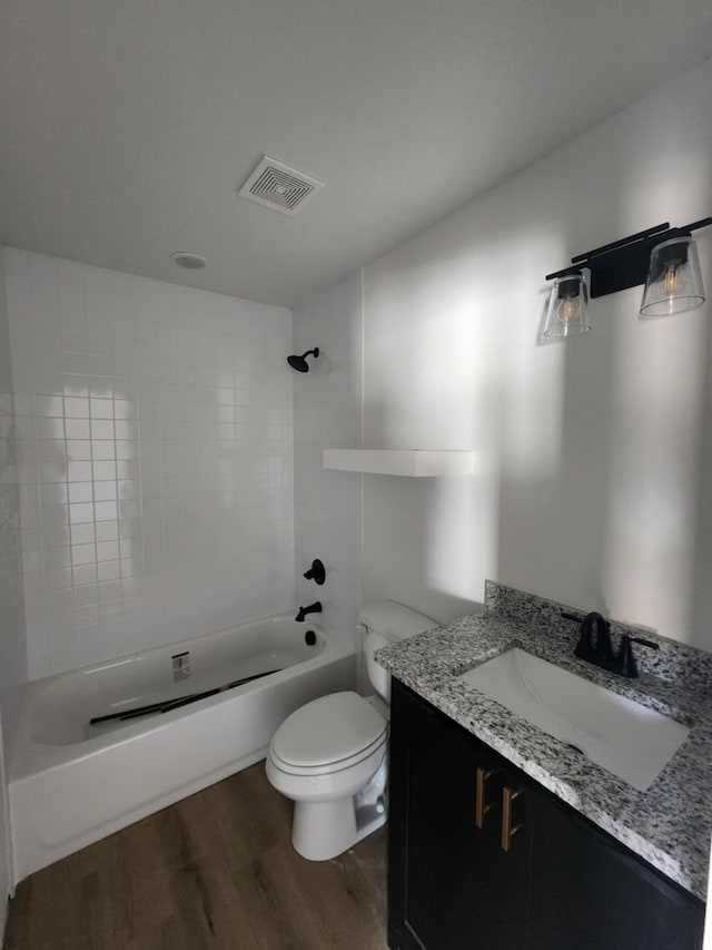 full bathroom featuring toilet, wood-type flooring, vanity, and tiled shower / bath combo