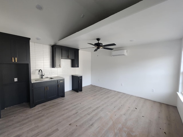 kitchen with light wood-type flooring, an AC wall unit, ceiling fan, and sink