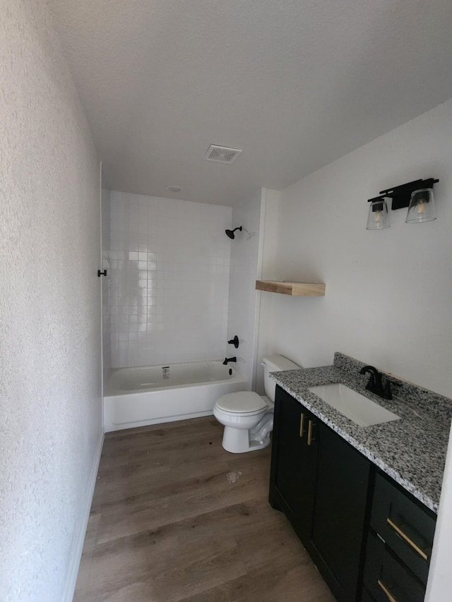 full bathroom with vanity, a textured ceiling, tiled shower / bath combo, wood-type flooring, and toilet