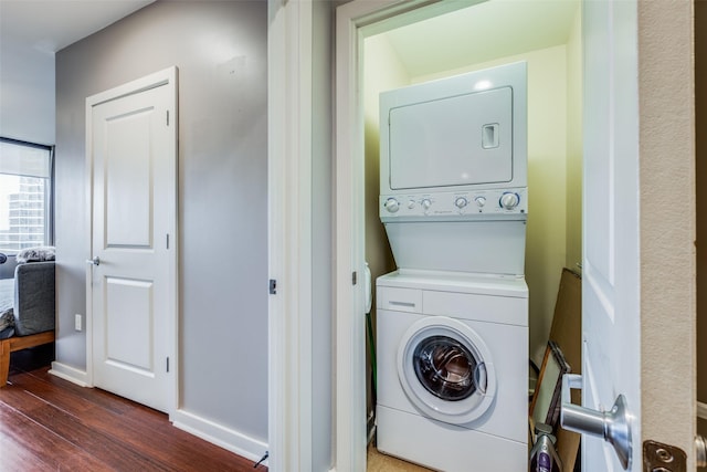 washroom with stacked washer / drying machine and dark hardwood / wood-style flooring