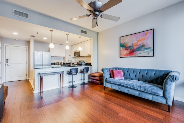 living room with ceiling fan, sink, and dark hardwood / wood-style floors