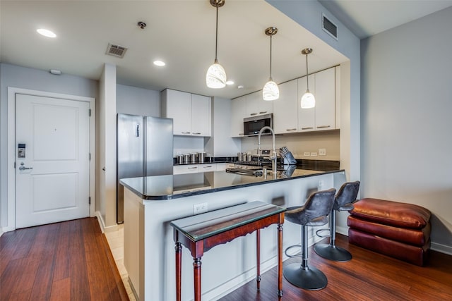 kitchen featuring white cabinetry, hanging light fixtures, dark hardwood / wood-style floors, and appliances with stainless steel finishes