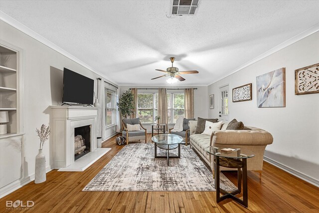 living room featuring hardwood / wood-style floors, ceiling fan, crown molding, and a textured ceiling