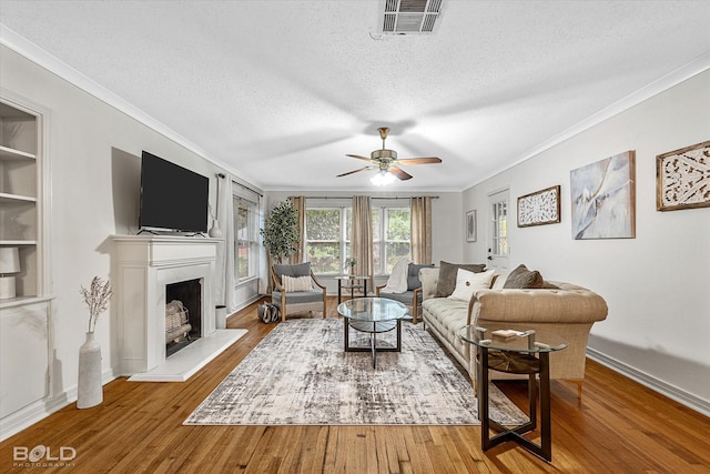 living room featuring crown molding, hardwood / wood-style flooring, ceiling fan, a textured ceiling, and built in shelves