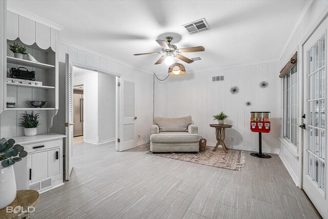 living area featuring crown molding, built in features, and ceiling fan