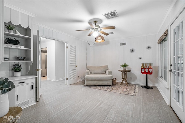 sitting room featuring crown molding, ceiling fan, and built in shelves