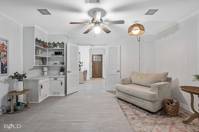 living room with wood walls, ornamental molding, and sink