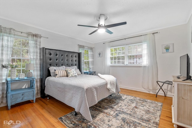 bedroom featuring ceiling fan, ornamental molding, hardwood / wood-style floors, and multiple windows