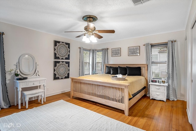 bedroom with a textured ceiling, hardwood / wood-style flooring, ceiling fan, and crown molding