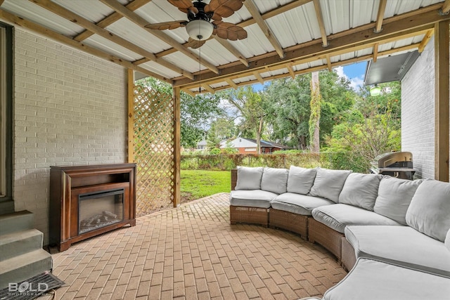 view of patio / terrace featuring ceiling fan and an outdoor living space with a fireplace