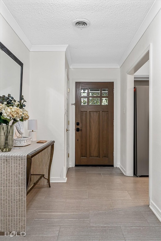 foyer entrance featuring ornamental molding and a textured ceiling